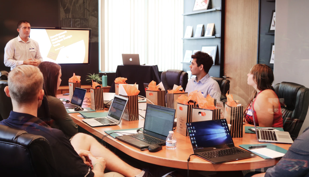 Work colleagues in a meeting sat around a long oblong table